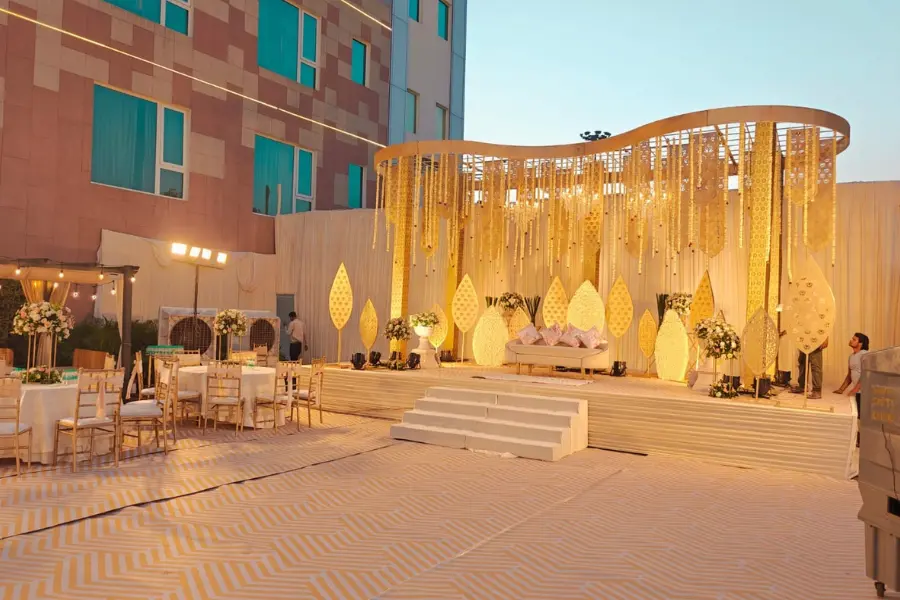 Beautifully lit wedding stage with golden drapery and floral arrangements at ExpoInn Suites and Convention.