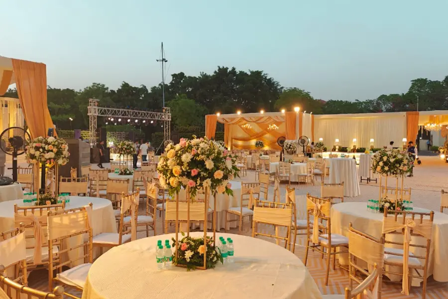 Outdoor wedding seating arrangement with tall floral centerpieces, round tables, and evening sky lighting